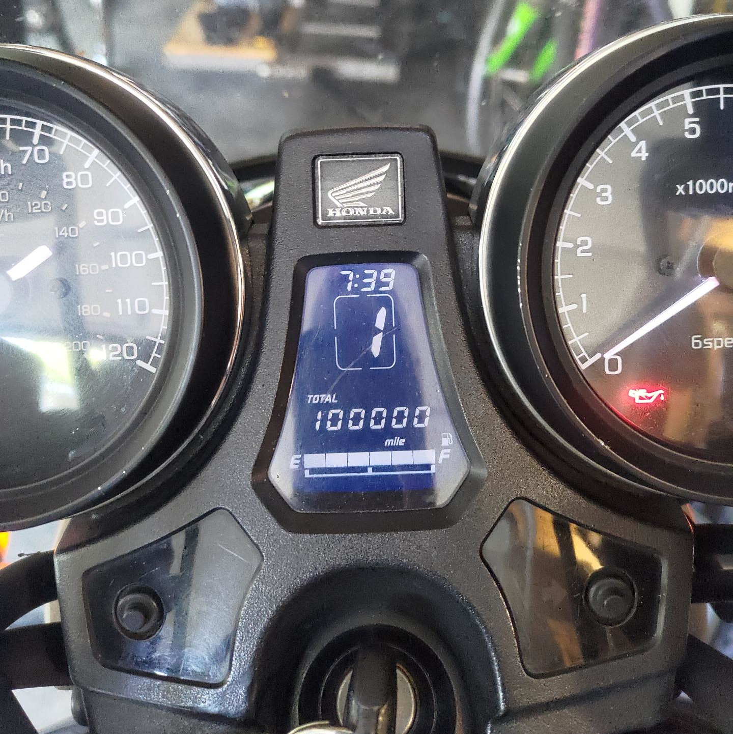 A motorcycle cockpit. A digital odometer right in the center reads 100,000 miles!