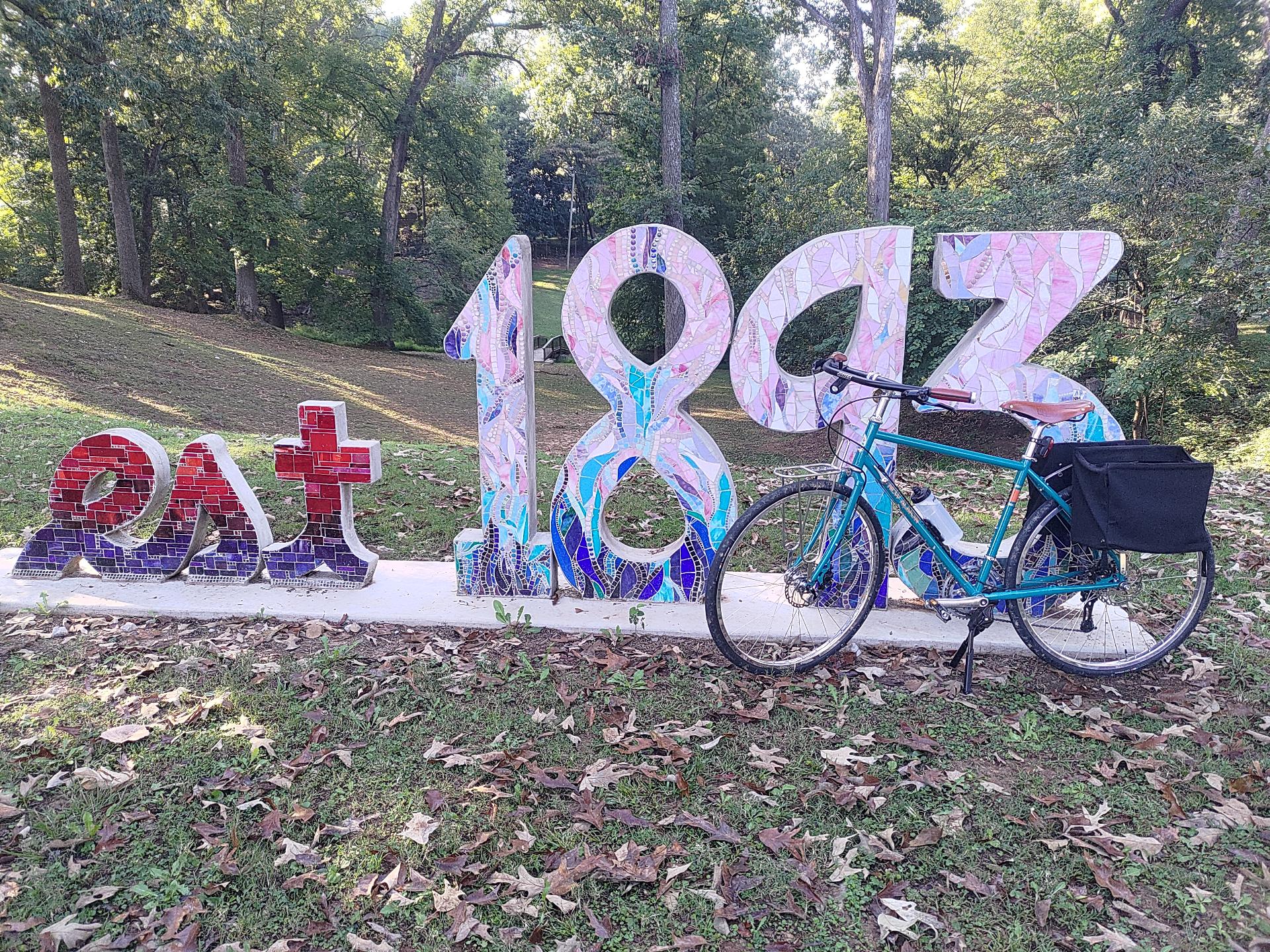 A sculpture of the words 'est 1893' with a blue bicycle in front of it