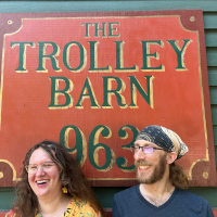 A picture of Sam and Valerie laughing in front of a sign that says 'The Trolley Barn 963' on a flier that has the address of the trolley barn and the dates the dance happened.
